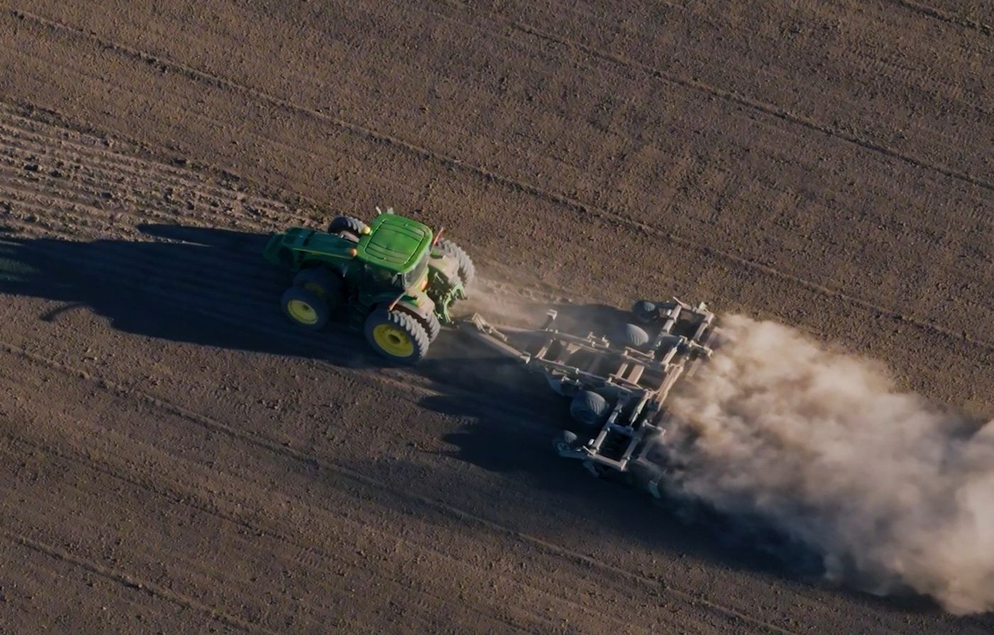 Aerial view of an APEX Hyperdisc T Series and tractor working a field with a long dust trail